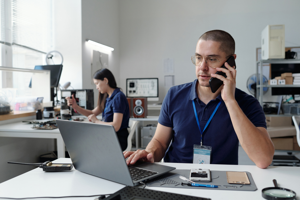Staff member using a phone and laptop in an office setting